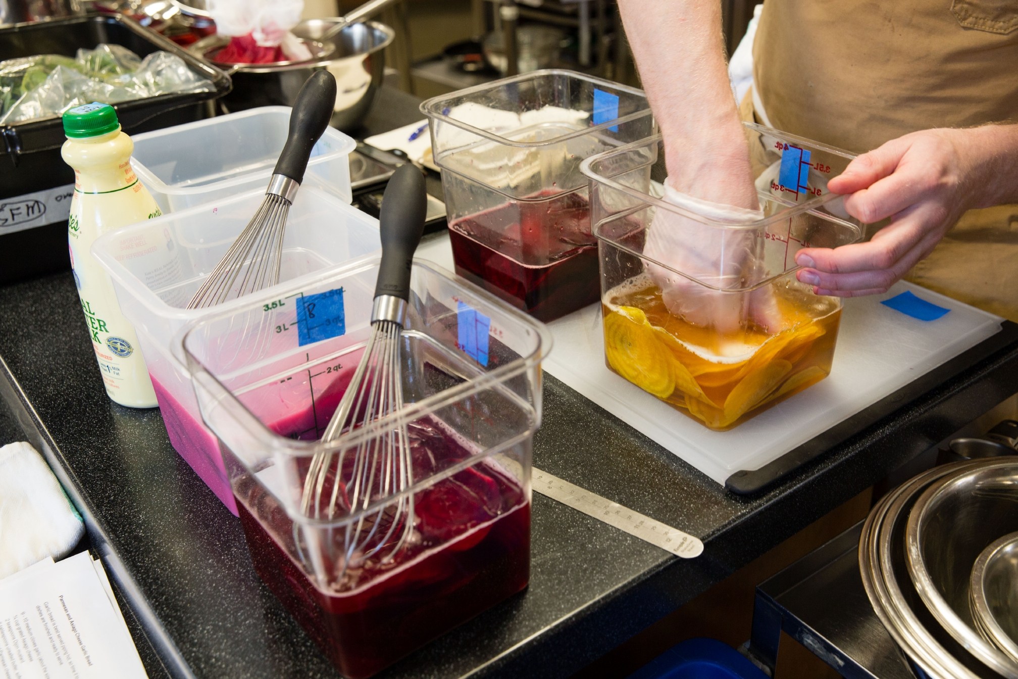 Cook's Science test cook Sasha Marx uses his hands to agitate thinly sliced golden beets sitting in a lemon juice-based liquid as he experiments with different methods for making beet kvass, a traditional fermented beverage from the Baltics.