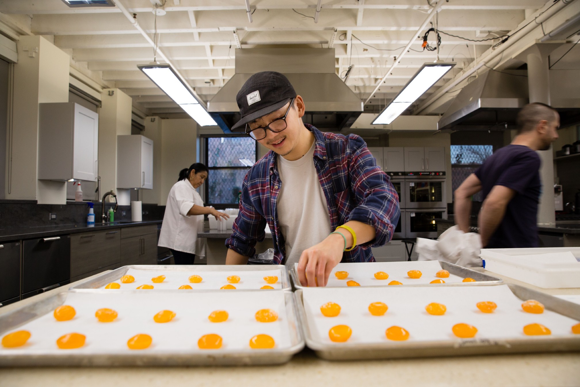 Associate Cook's Science editor Tim Chin arranges a cured egg yolk on a sheet tray containing several other samples while preparing a tasting of egg yolks cured in different mixtures of salt and sugar, plus maple syrup, soy, and miso, for varying lengths of time.
